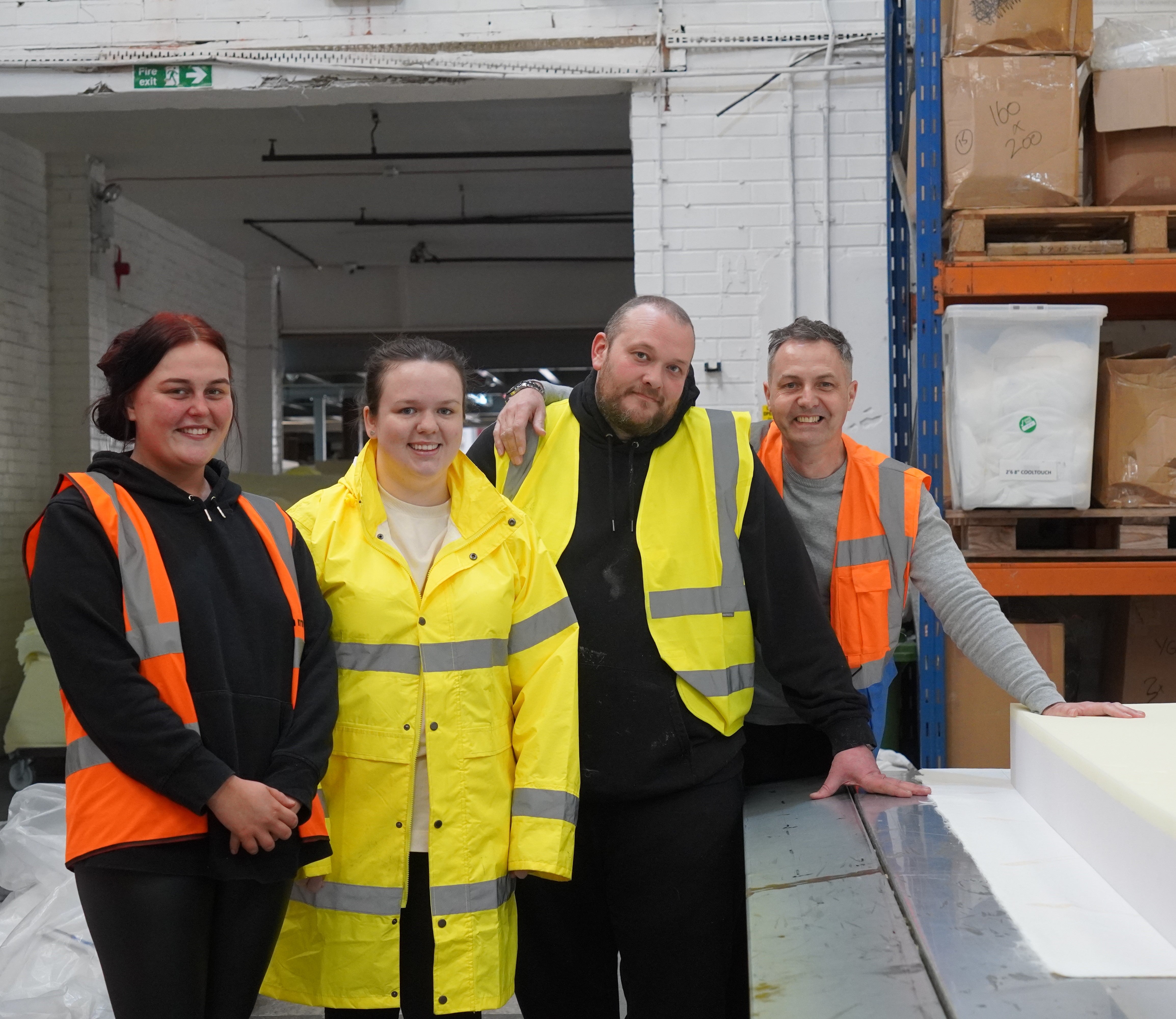 Four members of our team including sales, admin and production staff stand with one of our foam mattresses.